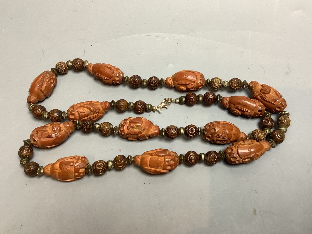 A Chinese peach stone or nut bead necklace, bracelet, a pair of earrings and two carved beads